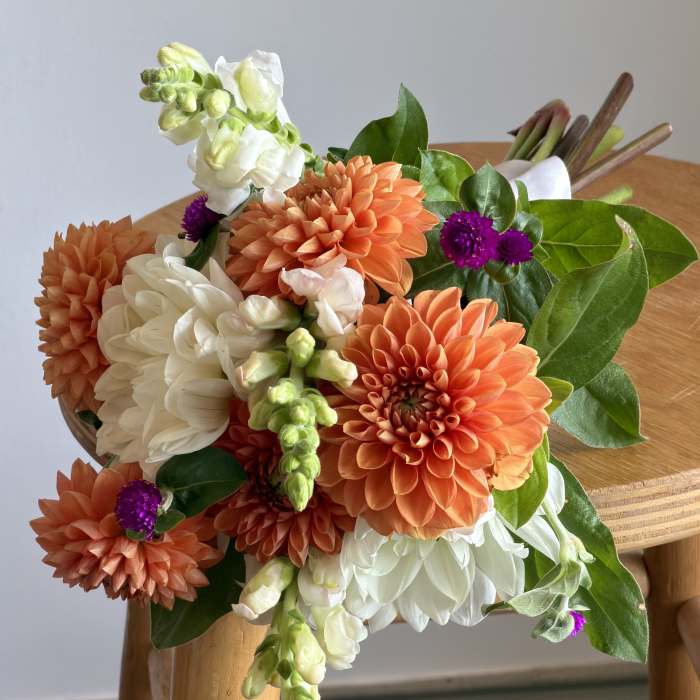 Bouquet of orange and white flowers with green leaves on a wooden chair