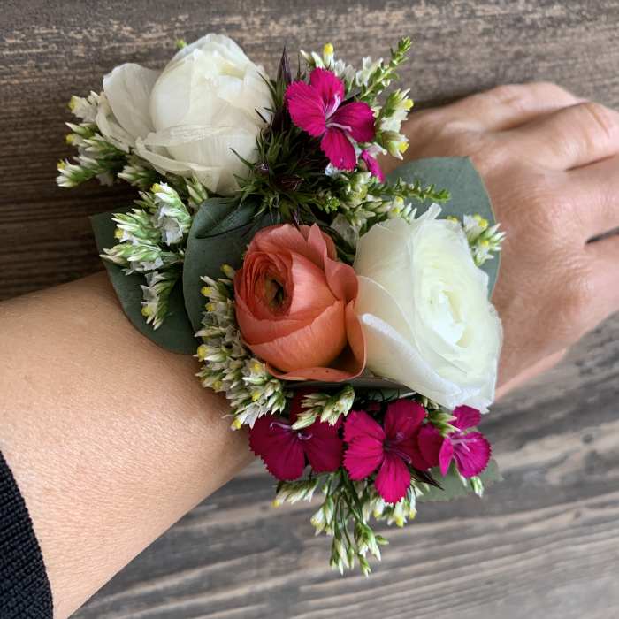 Small wrist corsage with white, coral, and bright pink flowers