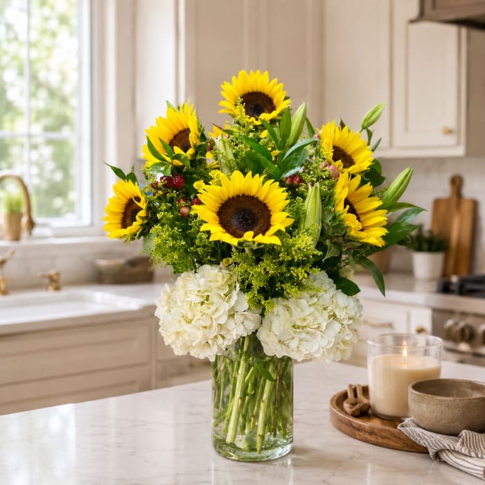 Sunflower and white hydrangea arrangement in a clear glass vase