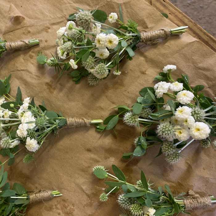 Small white flower bouquets with green foliage wrapped in twine