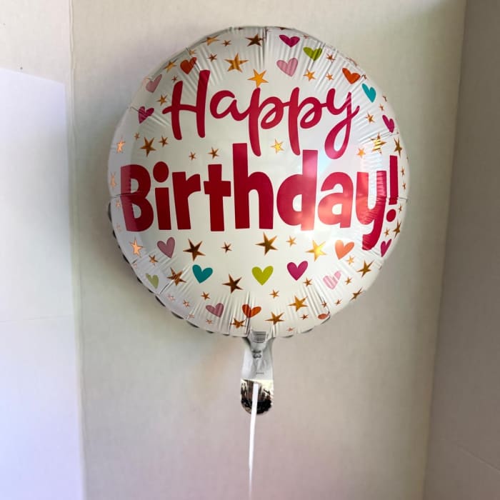 Round foil balloon reading Happy Birthday with heart and star confetti