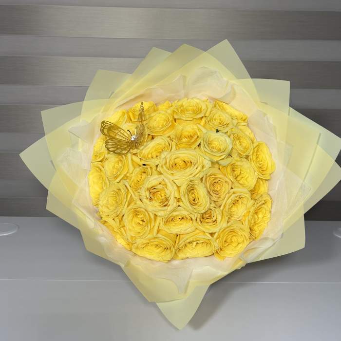 Bouquet of yellow roses wrapped in pale yellow paper with a butterfly decoration