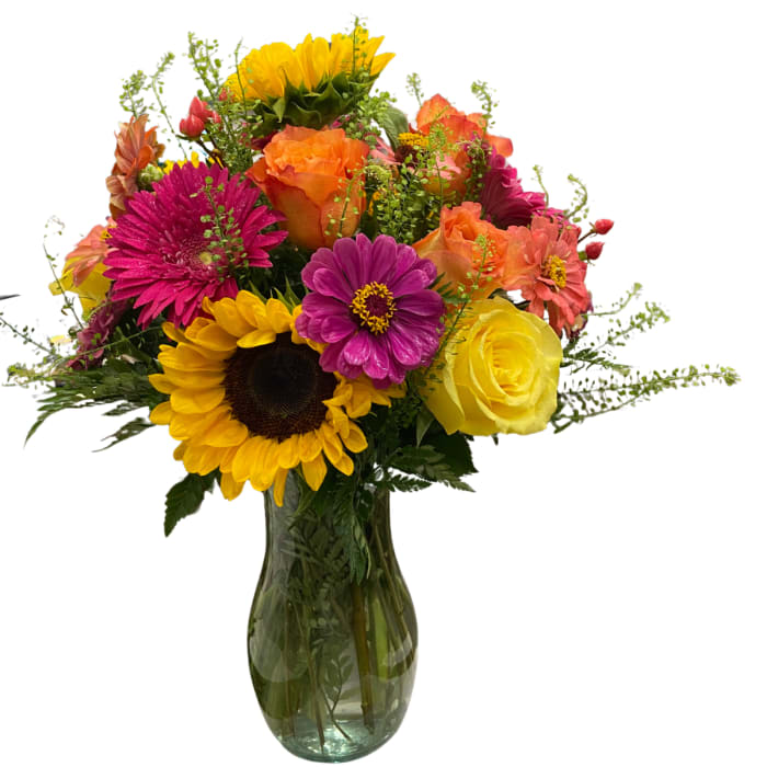 Mixed bouquet of sunflowers, roses, and daisies in a glass vase
