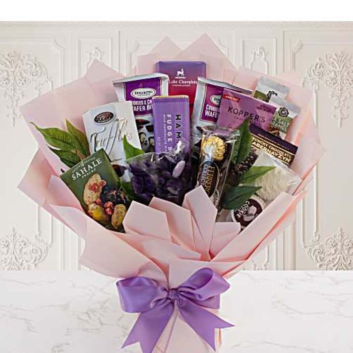 Gift bouquet of assorted chocolates and snacks wrapped in pink paper with a purple bow