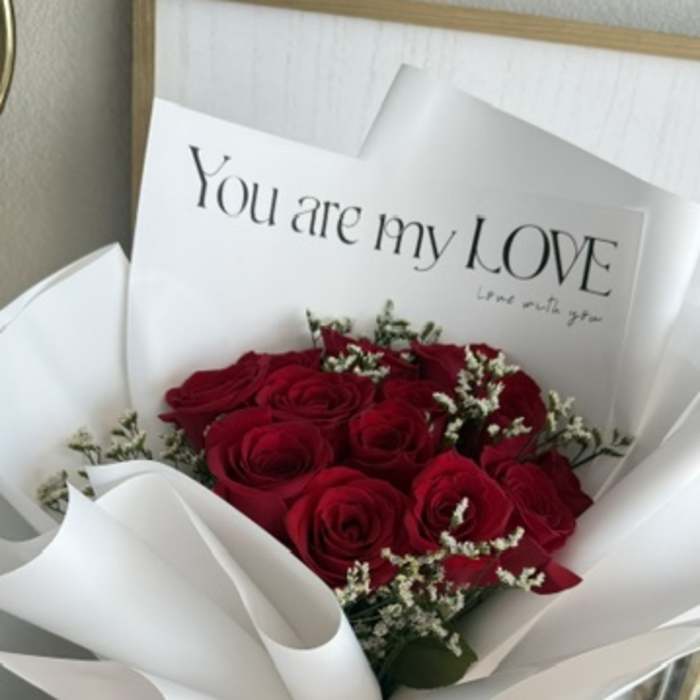 Bouquet of red roses wrapped in white paper with a love card