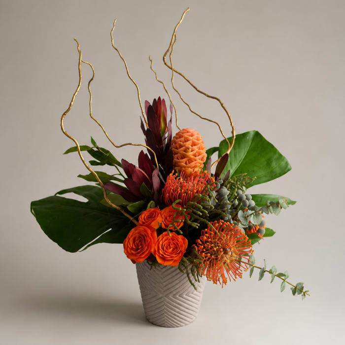 Orange and burgundy tropical flowers in a textured vase