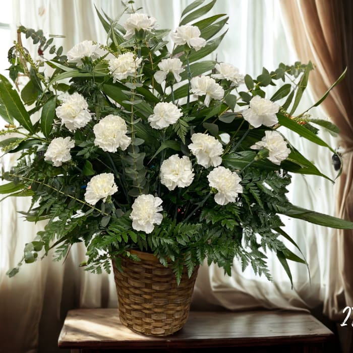 White carnations in a woven basket with mixed greenery