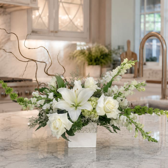 White floral arrangement in a square vase with long twisting branches