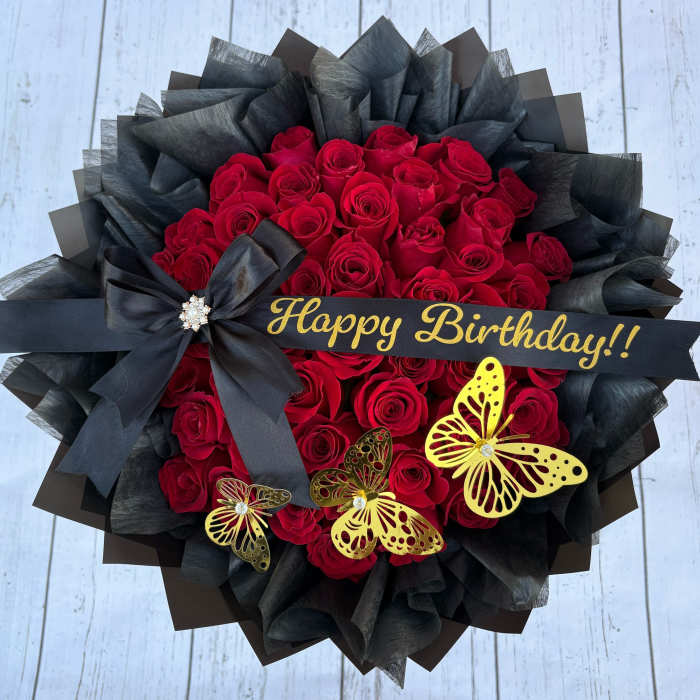 Red rose bouquet with black wrapping, a birthday ribbon, and butterfly decorations