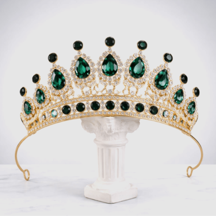 Gold tiara with green gemstones on a white pedestal