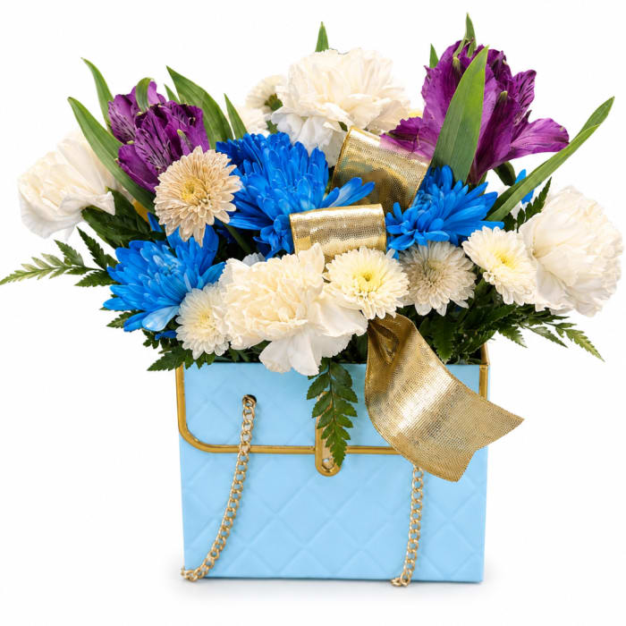 Blue box arrangement with white, purple, and blue flowers and a gold ribbon