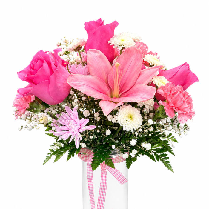 Pink mixed flower bouquet in a clear glass vase with a gingham ribbon