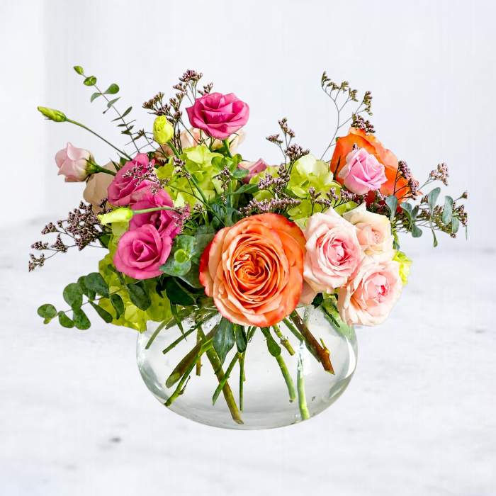 Mixed bouquet of roses and hydrangeas in a clear glass vase