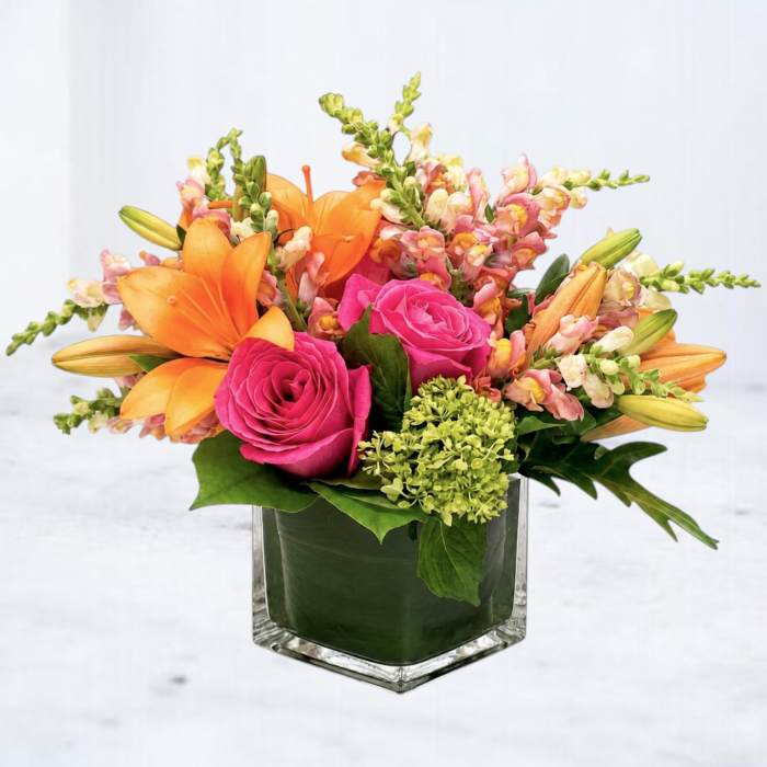 Pink roses and orange lilies in a square glass vase