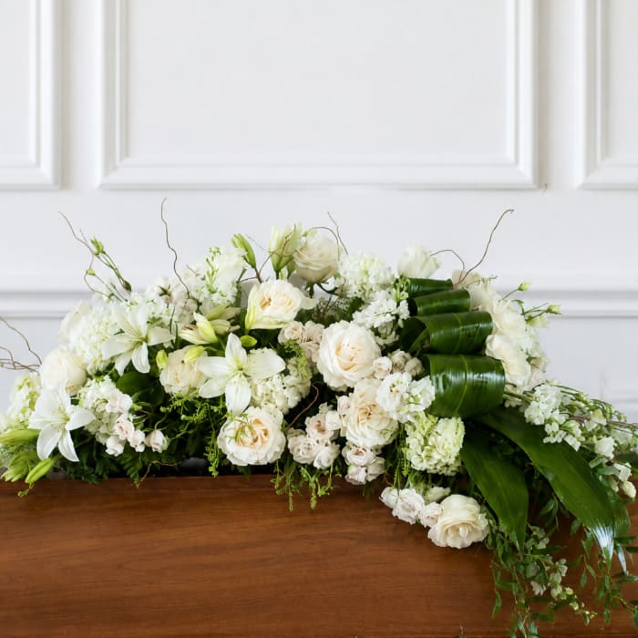 White floral casket spray with roses and lilies