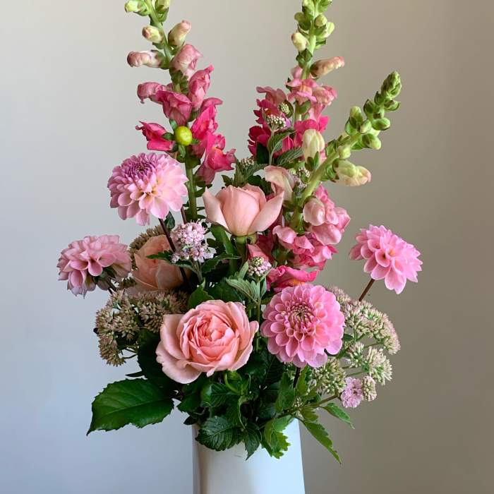 Pink and peach flowers arranged in a tall white vase