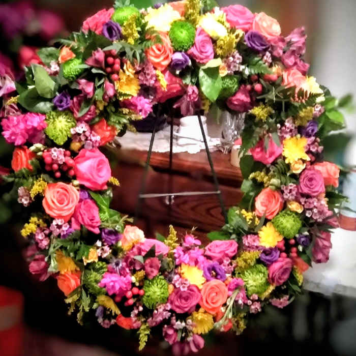 Colorful floral wreath with roses and mixed blooms on a stand