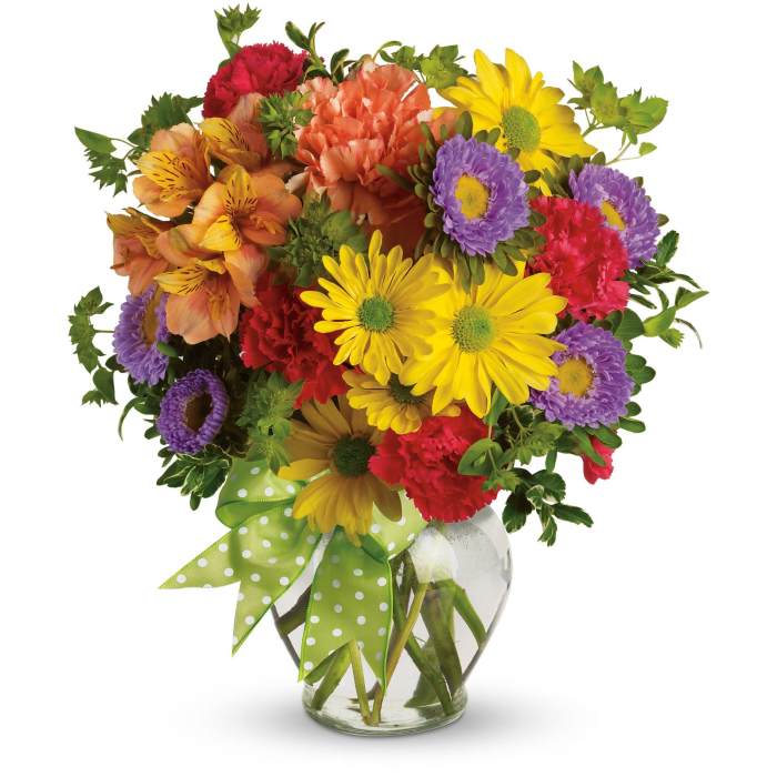 Bright mixed bouquet of yellow daisies, red carnations, and purple blooms in a clear vase with green ribbon.