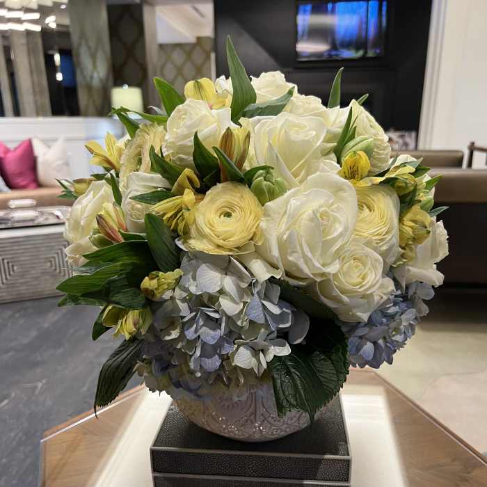 White roses and yellow flowers arranged in a decorative vase