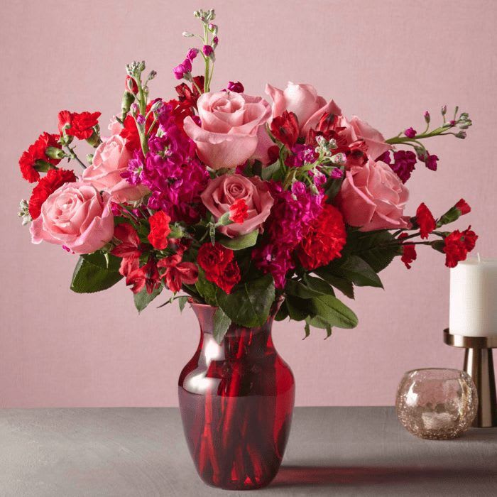 Pink and red flower arrangement in a red glass vase