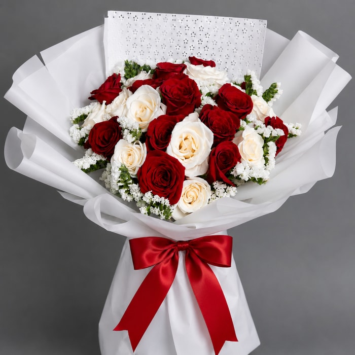 Bouquet of red and white roses wrapped in white paper with a red ribbon