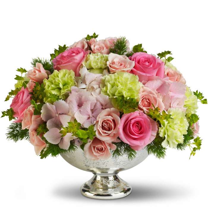 Pink and peach roses with green carnations in a silver pedestal bowl
