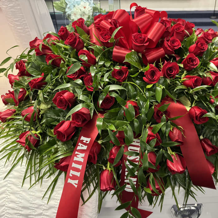 Large red rose arrangement with satin ribbons on a casket