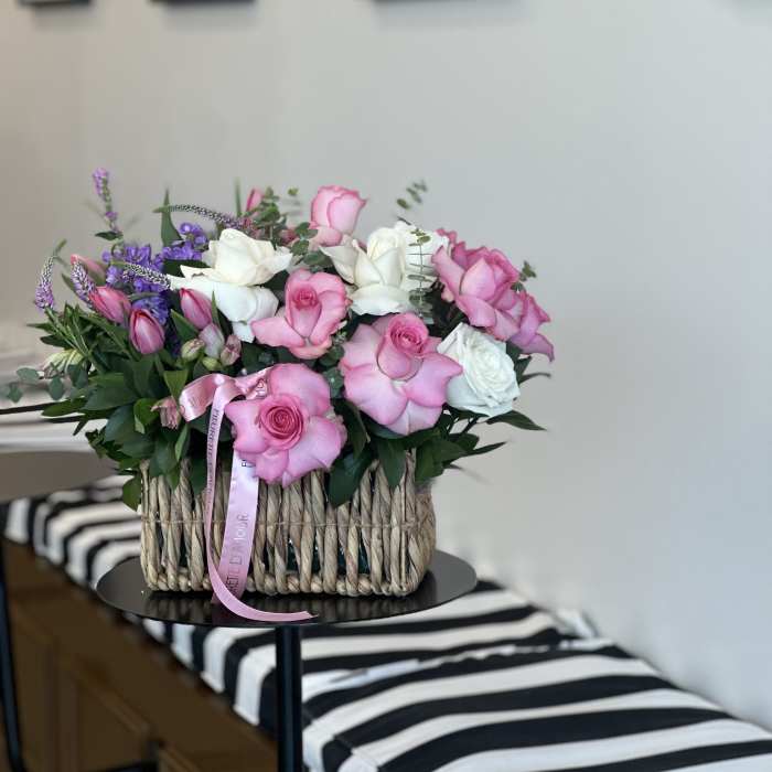 Pink and white roses arranged in a woven basket