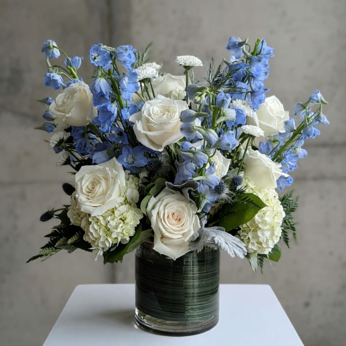 White roses and blue delphinium in a glass vase