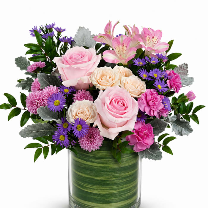 Pink and cream roses with purple daisies in a glass vase