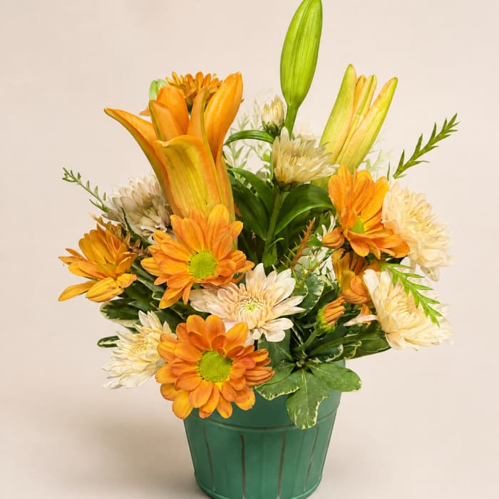Orange lilies and cream daisies in a green pot