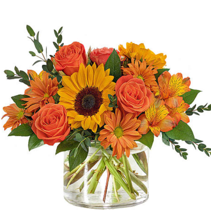 Orange roses and sunflowers in a clear glass vase