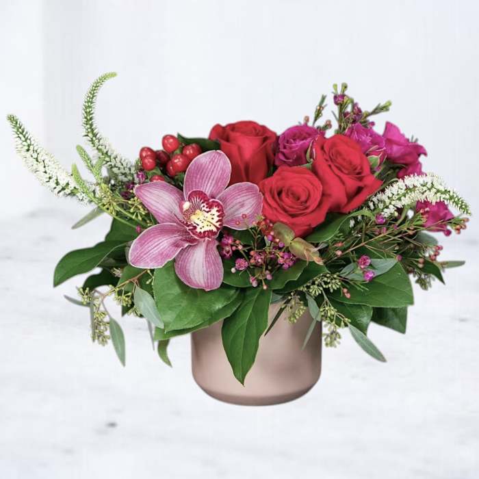 Pink and red roses with a pink orchid in a round vase