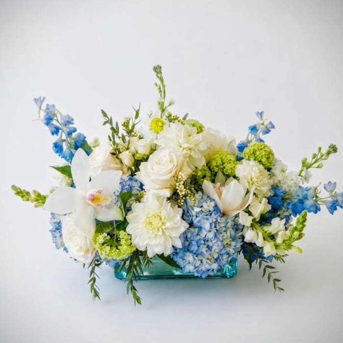 Blue and white floral arrangement in a turquoise glass vase