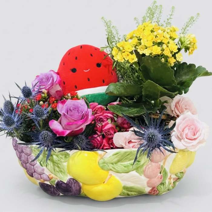 Mixed flower arrangement with a watermelon plush centerpiece in a painted ceramic container