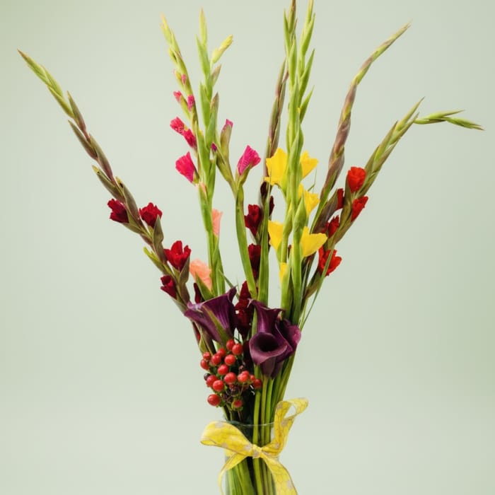 Tall mixed bouquet in a clear glass vase with a yellow ribbon