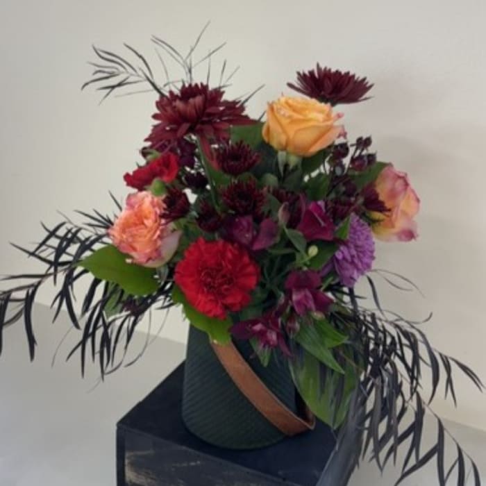 Mixed bouquet with roses and dark purple flowers in a vase