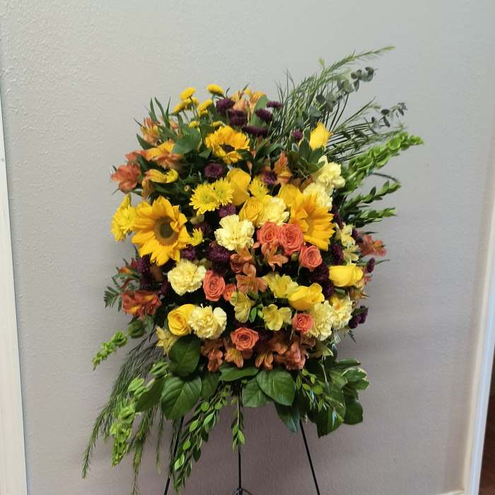 Large standing floral spray with yellow, peach, and purple blooms on an easel