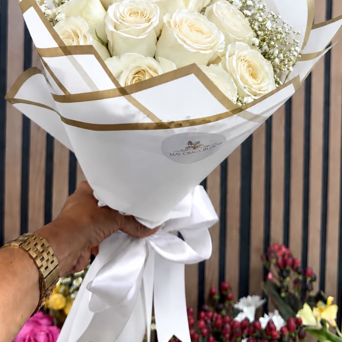 Bouquet of cream roses wrapped in white paper with gold trim