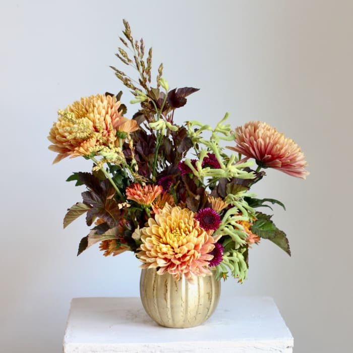 Autumn bouquet of peach and pink chrysanthemums in a gold vase