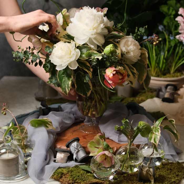 White and blush floral arrangement in a glass vase with small glass bud vases nearby