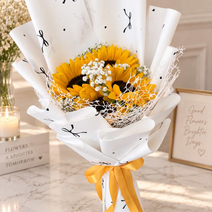 Bouquet of sunflowers wrapped in white paper with a yellow ribbon