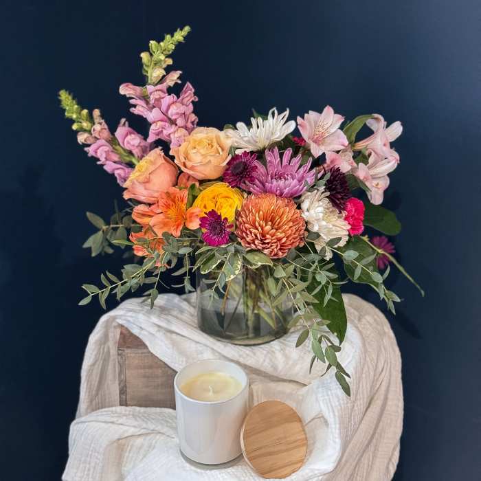 Mixed bouquet in a glass vase with a candle in front