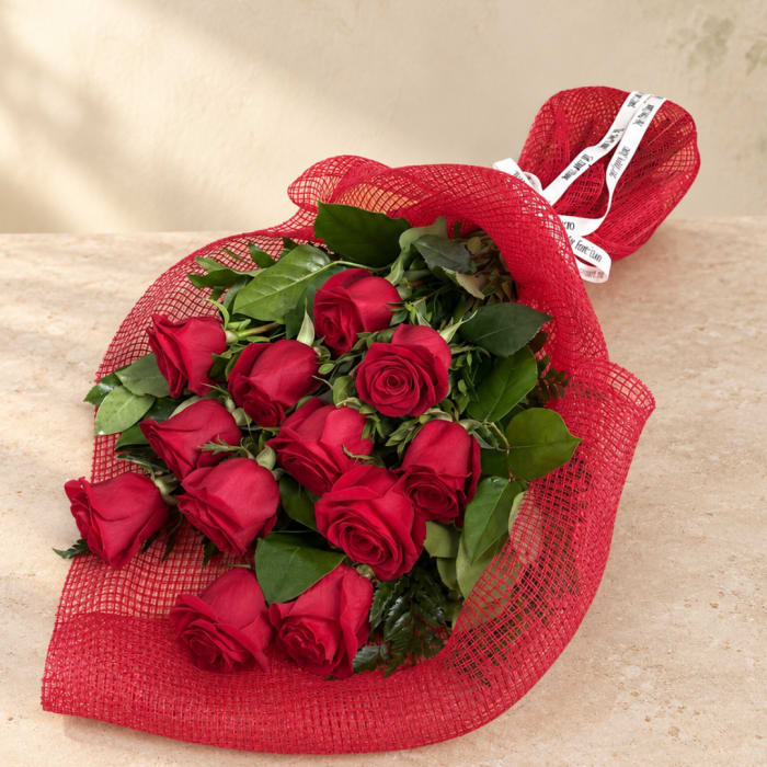 Bouquet of red roses wrapped in red mesh with a white ribbon