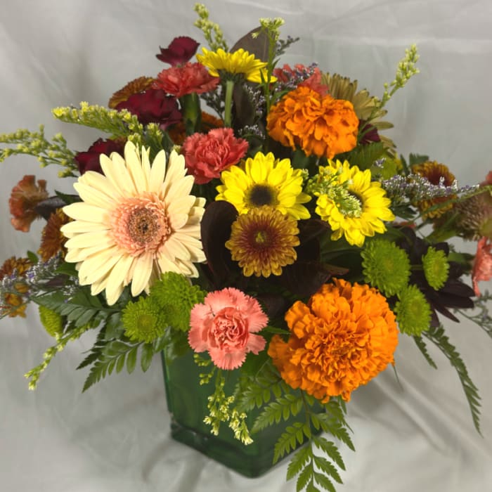 Mixed bouquet of gerbera daisies and carnations in a green glass vase