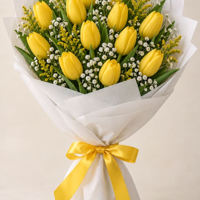 Bouquet of yellow tulips with white filler flowers wrapped in white paper