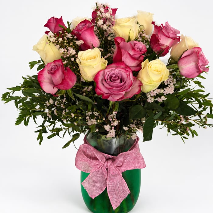 Pink and yellow roses in a green vase with a pink bow