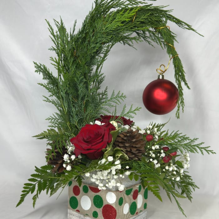 Holiday floral arrangement with a red rose, pinecones, and a hanging red ornament