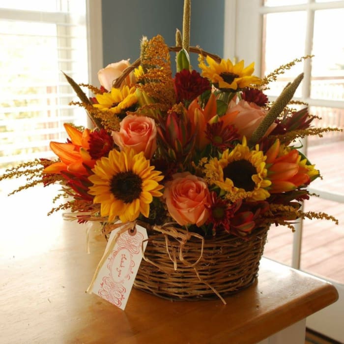 Basket arrangement of sunflowers, roses, and orange blooms