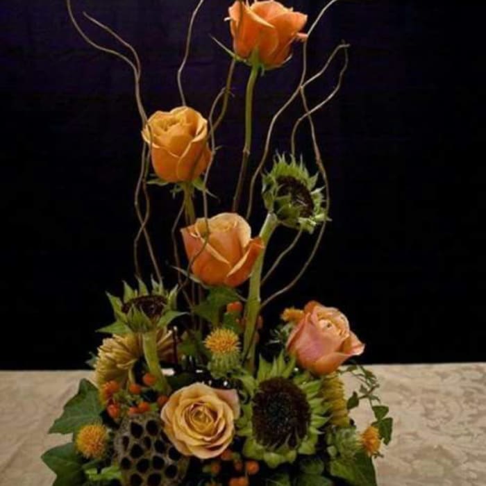 Orange roses and sunflowers in a tall floral arrangement